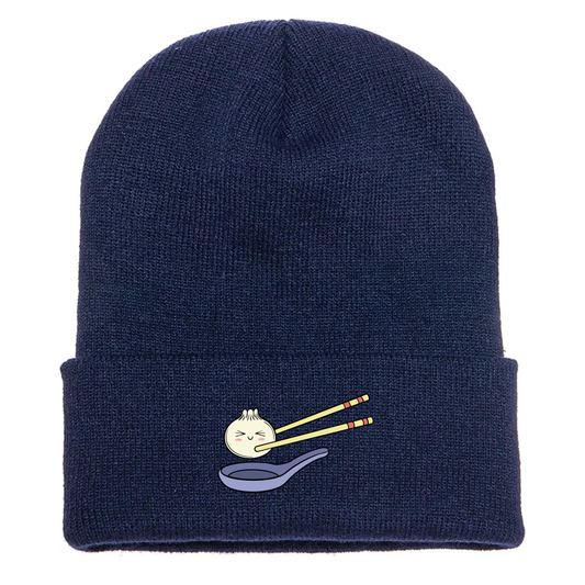 Navy acrylic cuffed beanie with a cute cartoon dumpling held by chopsticks over a blue soup spoon.