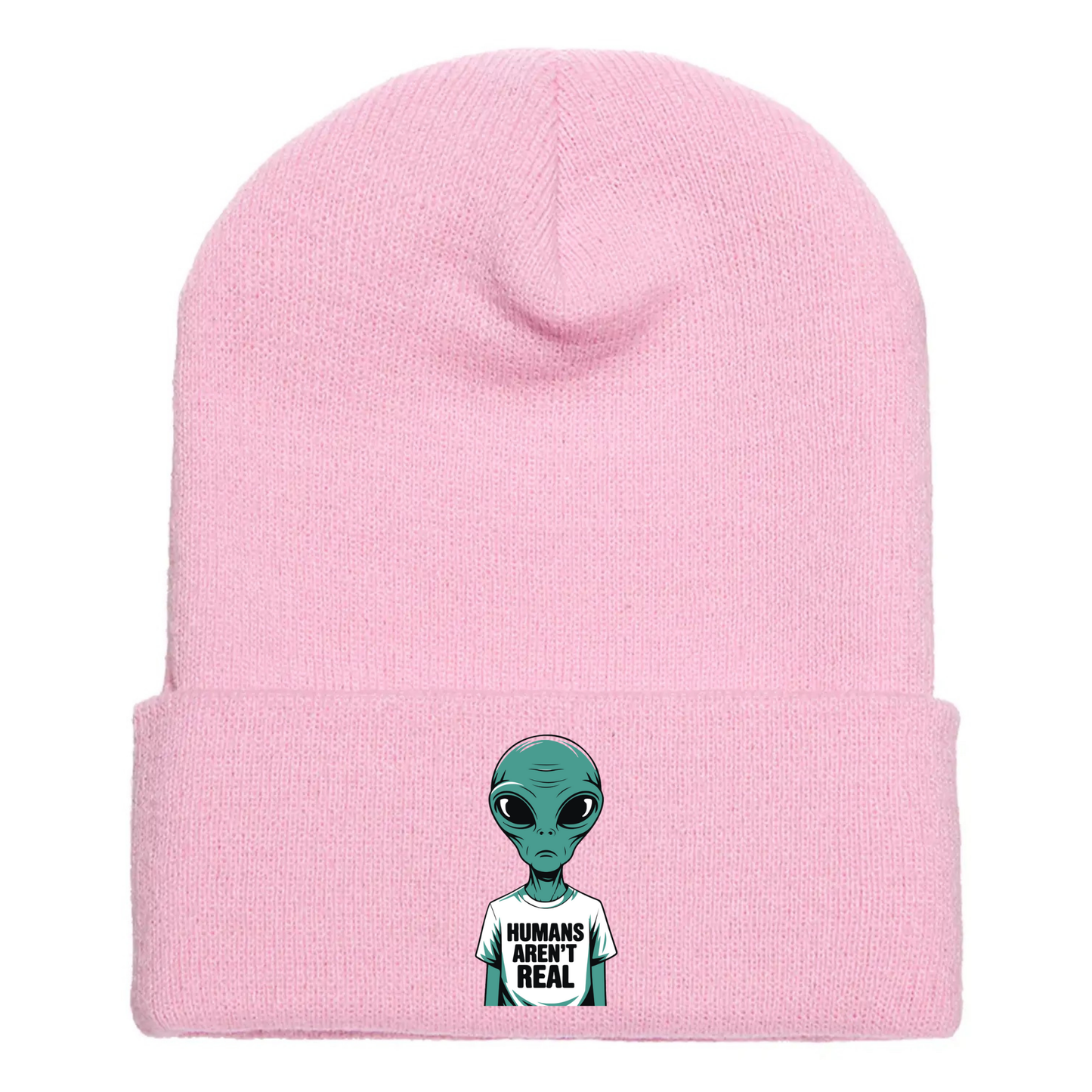 Pink acrylic beanie with a cartoon alien wearing a white T-shirt that says “Humans Aren’t Real” in bold black letters.